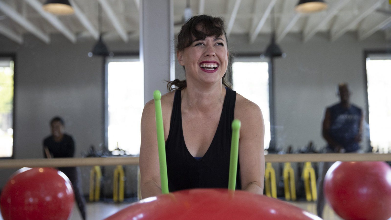 person hitting exercise ball with drum sticks