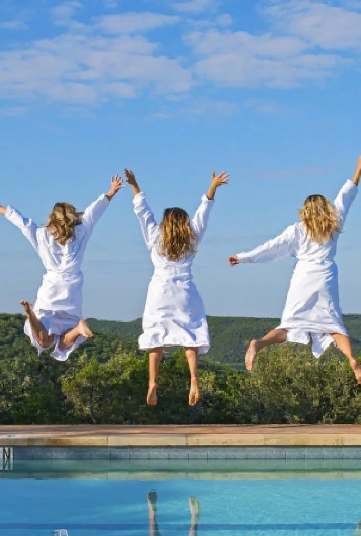 three people jumping by the pool