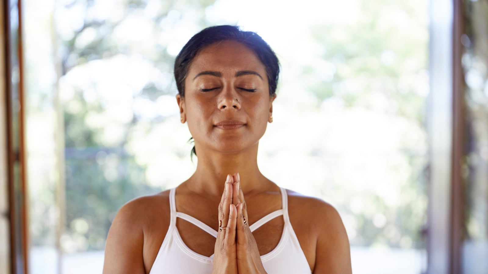 person with palms together and eyes closed