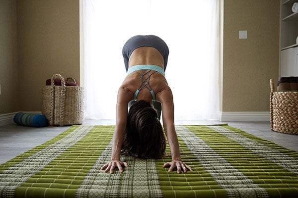 person doing downward dog yoga pose inside