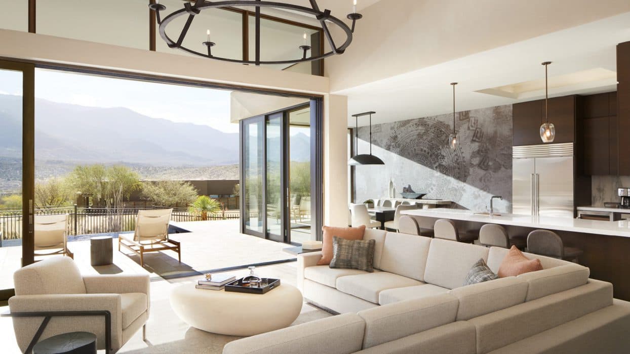 living room area with white couches and large open window with a landscape view