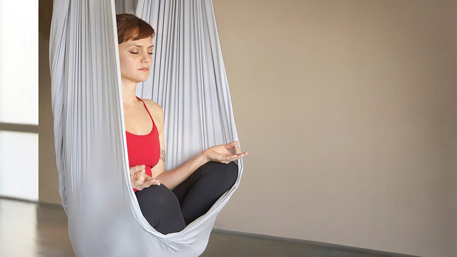 person meditating doing aerial yoga