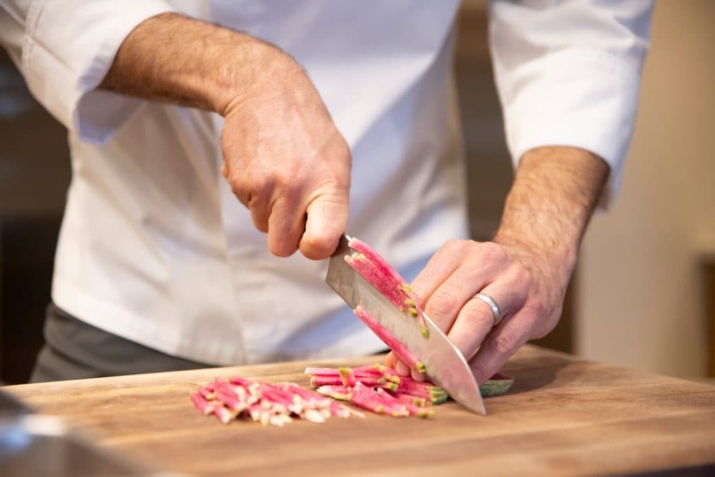 Closeup of chef's hands cutting meat with knife very fine