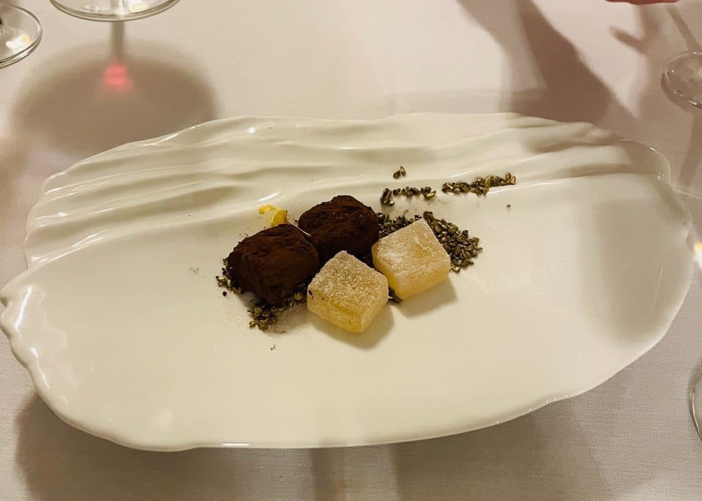 Lemon and honey truffles and chocolate sprinkled lychee pate de fruit on white plate