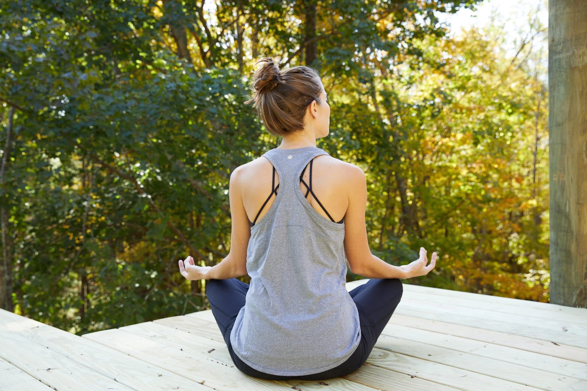 Woman in workout clothes sitting on patio doing yoga pose