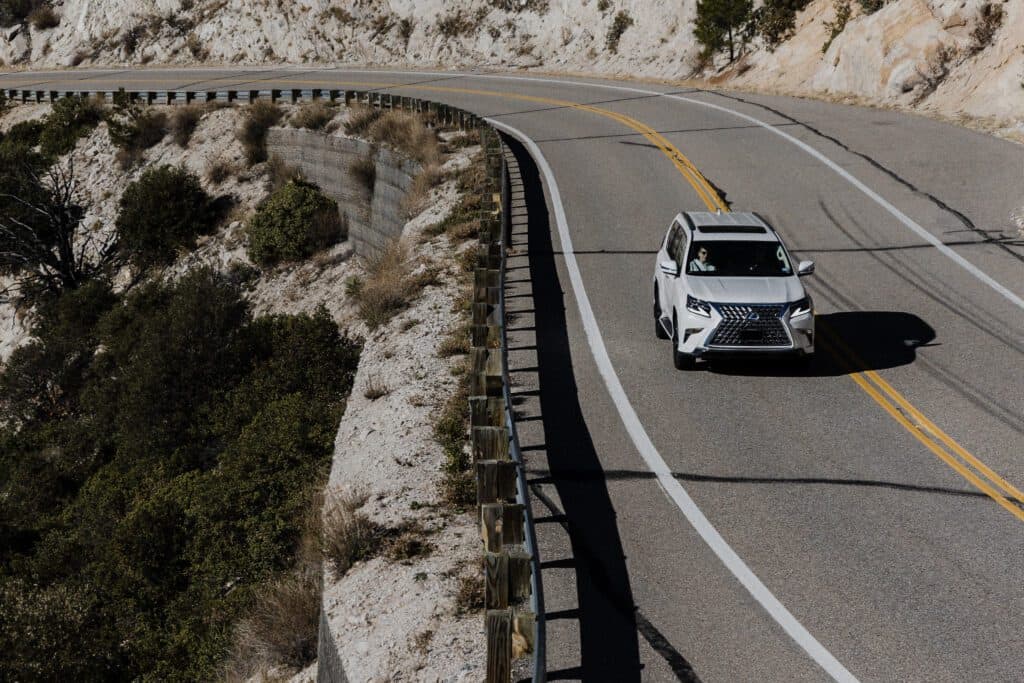 Lexus car driving on highway through mountains