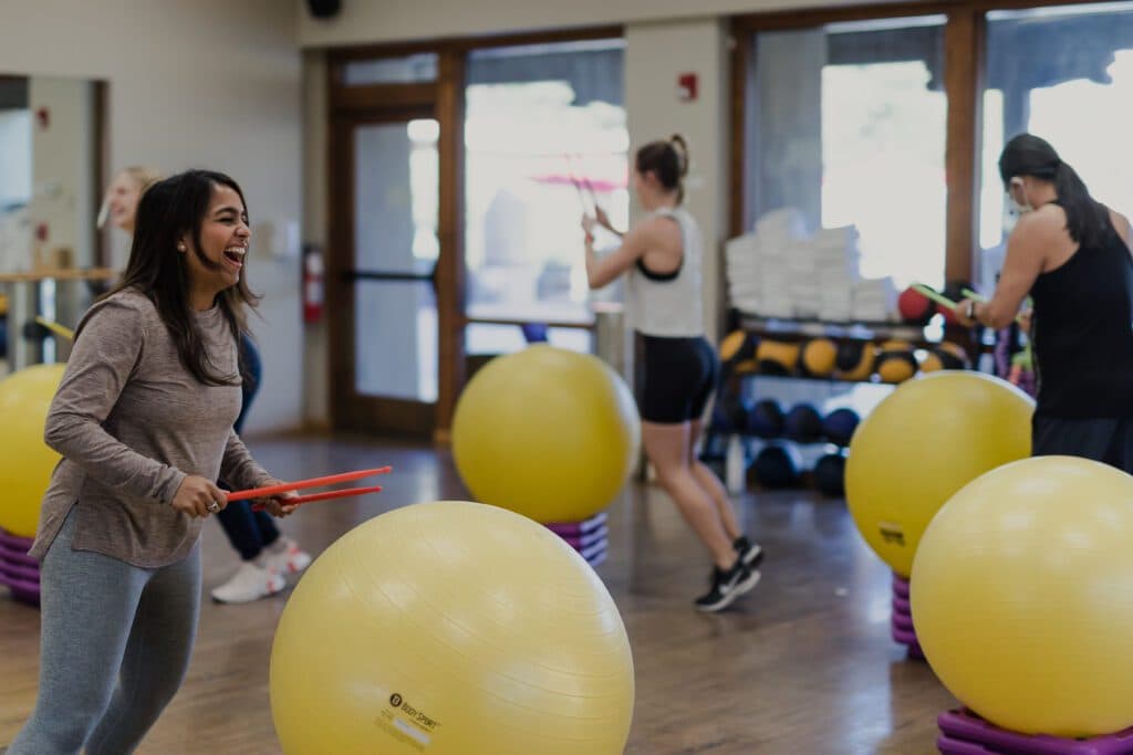 A group of people doing exercise with medicine balls and drumsticks